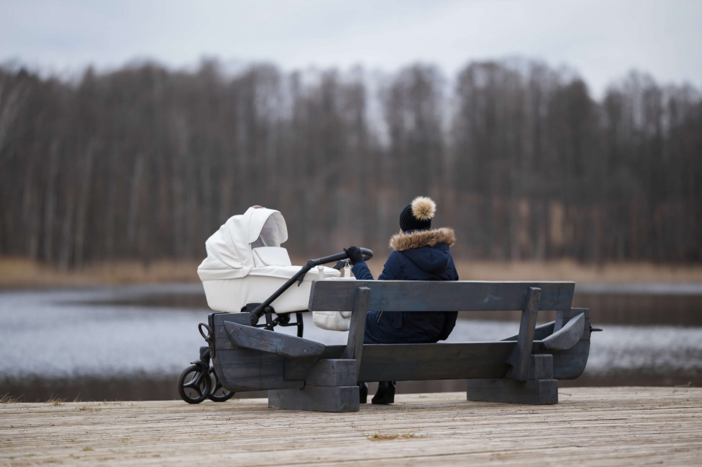 Mor med barnevogn sidder alene på en bænk. Foto: Shutterstock
