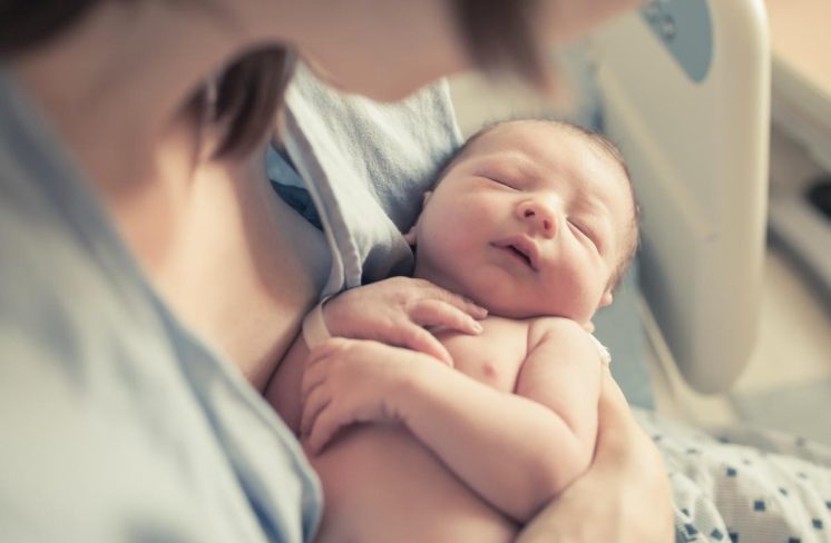 Nyfødt baby i mors arme på hospitalet